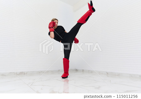 Full length authentic portrait of young European sporty woman doing boxing exercises, kicking isolated over white background. Full length authentic portrait of young European sporty woman doing boxing exercises, kicking isolated over white background. 115011256