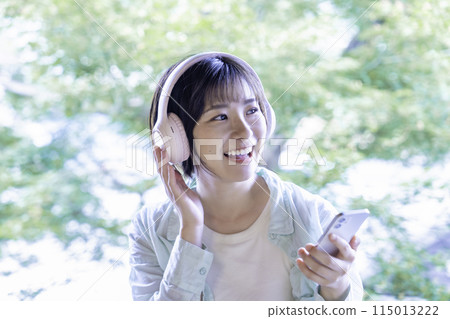 在智能手機上聽音樂的年輕女子帶耳機 115013222