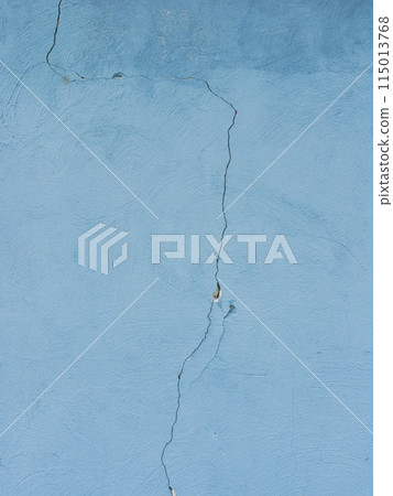 A large crack in the old blue plaster wall. 115013768