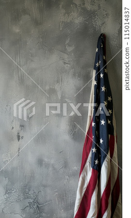 Draped American flag on a textured gray wall. Symbol of resilience and national pride for Independence Day themes. 115014837