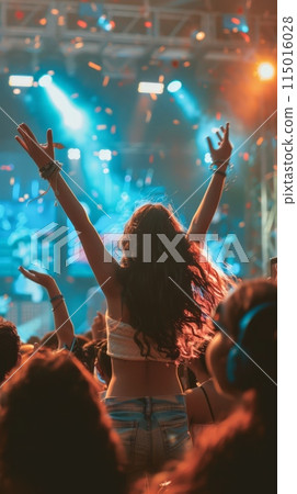 Energetic live concert with audience raising their hands towards the stage under colorful lights. Vibrant music event with dynamic atmosphere. 115016028