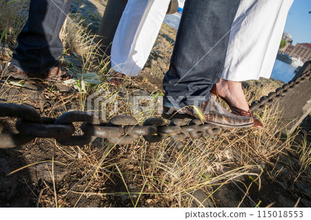 CloseUp of People Balancing on a Chain Outdoors in a Creative and Challenging Setting 115018553