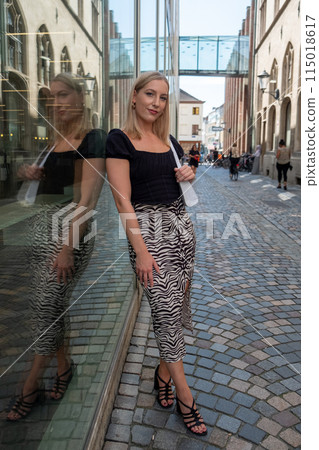 A stylish urban fashion photo featuring a woman photographed in a cobblestone alley 115018617