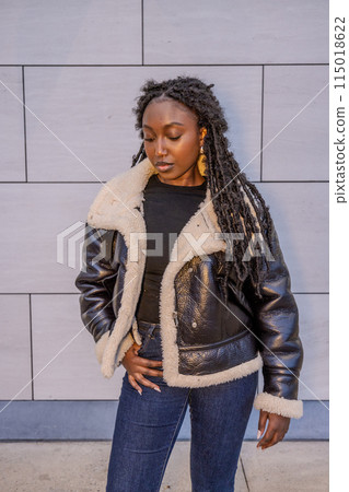 A fashionable woman looks stylish in a black jacket with a neutral gray background A fashionable woman looks stylish in a black jacket with a neutral gray background 115018622