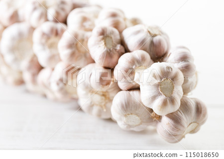Ripe organic garlic clove and bulb on white wooden background. Close-up. Selective focus. Ripe organic garlic clove and bulb on white wooden background. Close-up. Selective focus. 115018650