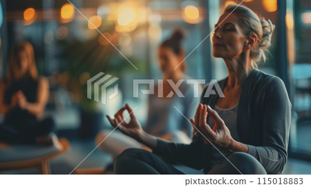 Women meditating in a serene, softly lit environment. Group meditation session for mental wellness and stress relief. 115018883