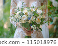 Close up of a woman holding a bouquet wearing a white wedding dress. 115018976