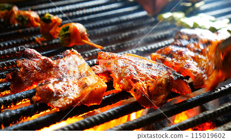 BBQ Barbecue grilled meat stick on fire flame with hot charcoal cooking outside. Beef grilling picnic outdoor with smoke bacon spicy sausage for party. Grill pork bbq on fire flame BBQ Barbecue grilled meat stick on fire flame with hot charcoal cooking outside. Beef grilling picnic outdoor with smoke bacon spicy sausage for party. Grill pork bbq on fire flame 115019602