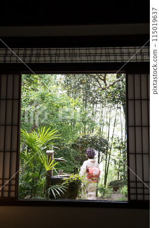 A woman in a kimono standing in a garden (back view) 115019637