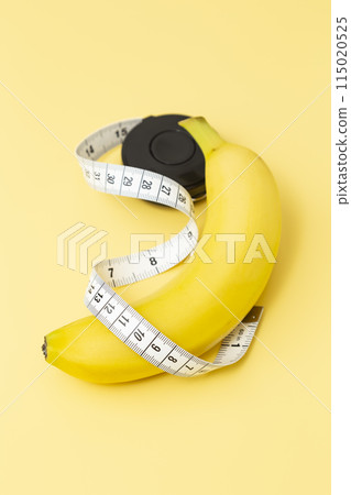 Banana and tape measure on a yellow background Banana and tape measure on a yellow background 115020525