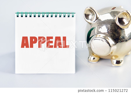 Appeal concept. Text APPEAL written on a notebook with a piggy bank next to it Appeal concept. Text APPEAL written on a notebook with a piggy bank next to it 115021272