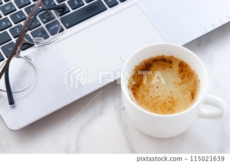 一名辦公室職員在辦公桌前用筆記型電腦工作,同時喝著美味的拿鐵咖啡的圖片 一名辦公室職員在辦公桌前用筆記型電腦工作,同時喝著美味的拿鐵咖啡的圖片 115021639