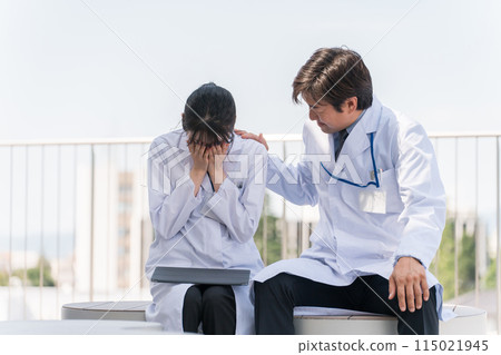 屋頂上一位沮喪/哭泣的女醫生和她的高級/老闆男醫生安慰/鼓勵她 屋頂上一位沮喪/哭泣的女醫生和她的高級/老闆男醫生安慰/鼓勵她 115021945