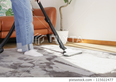 A woman vacuuming a room A woman vacuuming a room 115022477