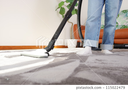 A woman vacuuming a room 115022479