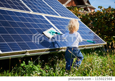 Small boy learning how to care about solar panels. Young kid cleaning new solar battery at warm sunny day. Concept of young generation and alternative energy. 115022568