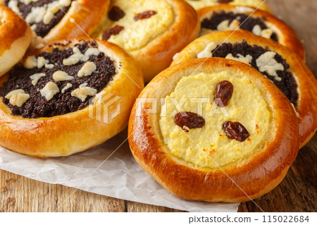 Homemade Czech kolach with traditional filling of cottage cheese with raisins and poppy seeds with streusel close-up on parchment. Horizontal Homemade Czech kolach with traditional filling of cottage cheese with raisins and poppy seeds with streusel close-up on parchment. Horizontal 115022684