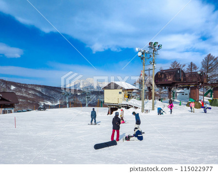Snowboarders preparing to ski down a slope on a clear day with Mount Myoko in the distance (Madarao Highlands, Nagano Prefecture) 115022977