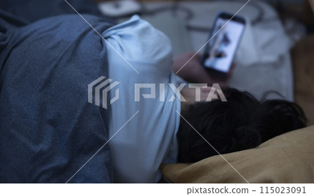 A child looking at a smartphone in bed 115023091