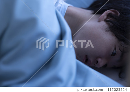 A child looking at a smartphone in bed 115023224