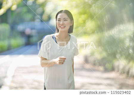 Smiling young woman running in sportswear 115023402