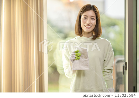 A middle-aged woman wiping windows in the living room A middle-aged woman wiping windows in the living room 115023594