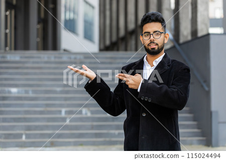 Indian businessman pointing empty place advertising area commercial text copy-space in city street 115024494