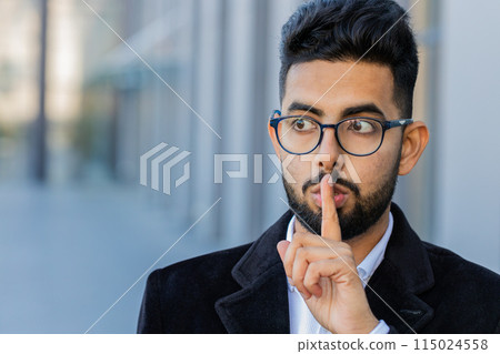 Business man presses finger to lips makes silence hush sign do not tells gossip secret quiet in city 115024558