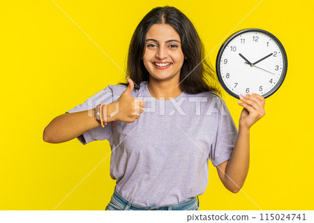 Indian young woman showing time hour on wall office clock, ok, thumb up, approve, hurry up, deadline 115024741