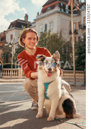 Young Caucasian bearded man walking in old city with purebred Aussie dog. Vertical orientation. Pet training and friendship with dog 115024787