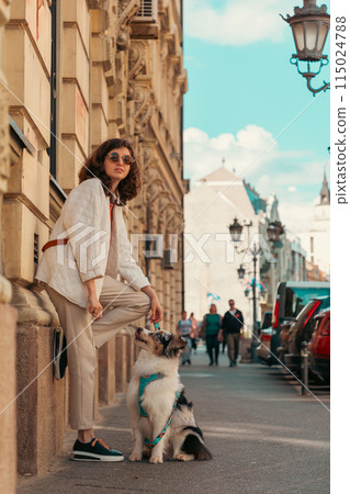 Young Caucasian pretty woman walking in city with purebred Aussie dog. Vertical orientation. Pet training 115024788