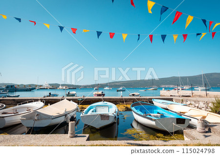 Beautiful sunny view of village pier with boats and flags on the Mediterranean coast. Summer vacation at resort and holidays 115024798