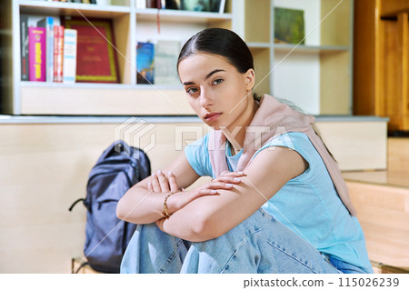 Serious teenage girl high school student sitting in class looking at camera 115026239