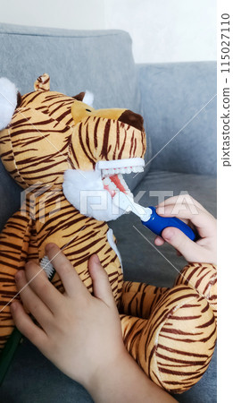A boy brushes his teeth with a toy with an artificial jaw. Playing as a dentist, professional preparation of a child for the profession of a pediatric dentist. Hygiene and dental care A boy brushes his teeth with a toy with an artificial jaw. Playing as a dentist, professional preparation of a child for the profession of a pediatric dentist. Hygiene and dental care 115027110