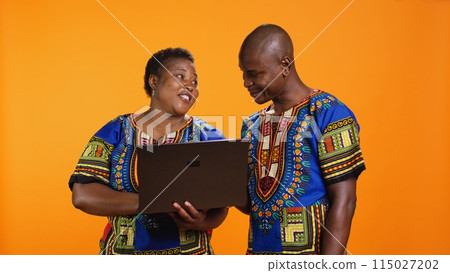 Husband and wife searching information on online website, holding laptop in front of camera for social media browsing. African american ethnic people using pc to check web browsers. Husband and wife searching information on online website, holding laptop in front of camera for social media browsing. African american ethnic people using pc to check web browsers. 115027202