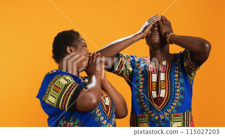 Cheerful african american couple laughing at thing in studio, having fun with jokes and being amused over background. Married ethnic people enjoying laugh on camera, joyful partners. Cheerful african american couple laughing at thing in studio, having fun with jokes and being amused over background. Married ethnic people enjoying laugh on camera, joyful partners. 115027203