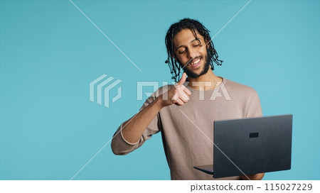Middle Eastern man greeting friend over online videocall on laptop, doing friendly gestures. Happy person bonding with mate using notebook to hold videoconference, studio background, camera A Middle Eastern man greeting friend over online videocall on laptop, doing friendly gestures. Happy person bonding with mate using notebook to hold videoconference, studio background, camera A 115027229