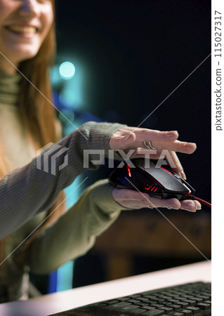 Joyous gen Z entertainer presenting wired gaming mouse from brand sponsoring video, urging viewers to buy it. Upbeat tech guru excited to promote computer peripherals to audience, close up Joyous gen Z entertainer presenting wired gaming mouse from brand sponsoring video, urging viewers to buy it. Upbeat tech guru excited to promote computer peripherals to audience, close up 115027317