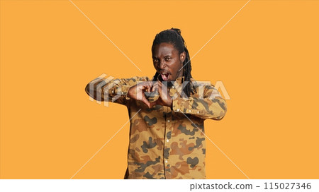 Male model presenting heart shape sign in studio, creating romantic flirty gesture to show his sincere emotions and feelings. Young adult doing love symbol on camera, romance concept. Male model presenting heart shape sign in studio, creating romantic flirty gesture to show his sincere emotions and feelings. Young adult doing love symbol on camera, romance concept. 115027346