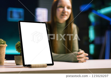 Focus on mockup tablet with gen Z teenager in blurry background doing review, comparing features. Close up shot of isolated screen portable device analyzed by influencer, filming online video Focus on mockup tablet with gen Z teenager in blurry background doing review, comparing features. Close up shot of isolated screen portable device analyzed by influencer, filming online video 115028207