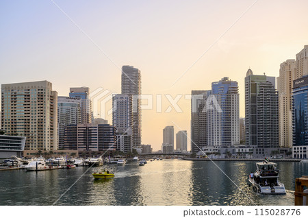 Sunset view of the canal, marina with boats, promenade and skyscrapers of Dubai, the Persian Gulf Sunset view of the canal, marina with boats, promenade and skyscrapers of Dubai, the Persian Gulf 115028776