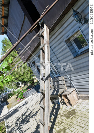 Wooden ladder leaning against an outbuilding in the backyard of a household Wooden ladder leaning against an outbuilding in the backyard of a household 115028948