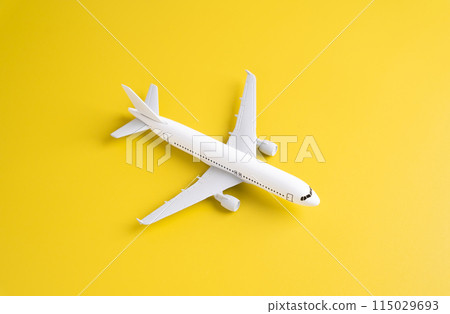 Passenger plane on a yellow background. Airplane figurine. Commercial flights Passenger plane on a yellow background. Airplane figurine. Commercial flights 115029693