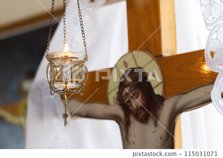 Burning candle against wooden cross with Jesus Christ. Selective focus. 115031071