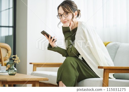 Woman with smartphone on sofa at home 115031275