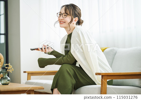 Woman with smartphone on sofa at home Woman with smartphone on sofa at home 115031276