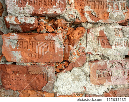 Old brick wall featuring the distinct stamp of the brick factory owner. The weathered bricks highlight the structure's historical significance and age. Old brick wall featuring the distinct stamp of the brick factory owner. The weathered bricks highlight the structure's historical significance and age. 115033285