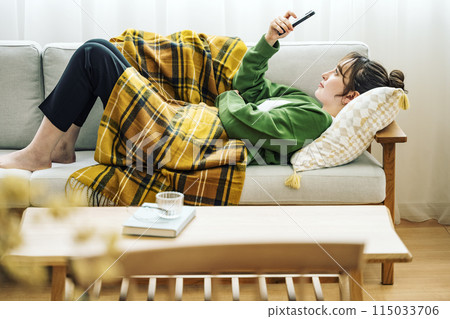 Woman looking at smartphone on sofa at home 115033706