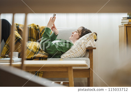 Woman looking at smartphone on sofa at home 115033712