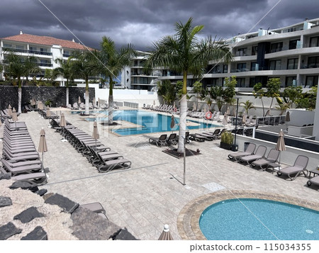 Relaxing rattan chairs with pillows beside swimming pool Tenerife 115034355